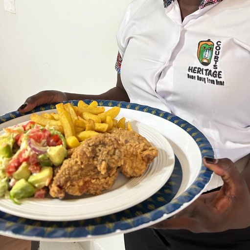 Southern fried chicken with potato chips and avocado salad, carried to the table by Heritage Hotels Arua staff