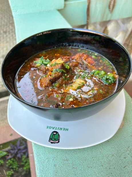 A bowl of slow cooked beef stew garnished with fresh herbs at Heritage Hotels Arua